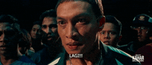 a group of men are looking at a man with the word lagi written on his face