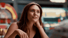 a close up of a woman sitting at a table with her hand on her chin .