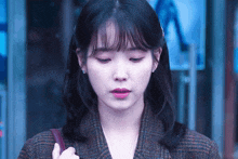 a close up of a woman 's face with a plaid jacket on