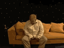 a man in a white shirt sits on a couch