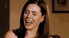 a woman is laughing with her mouth open .