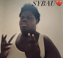 a man in a white tank top is standing in front of a poster that says sybau