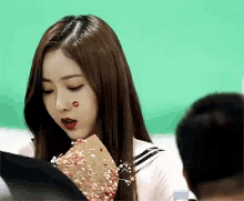 a girl with a red heart on her face is holding a piece of paper
