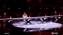 a group of people sitting in front of a sign that says x on it