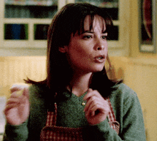 a woman wearing an apron and a green sweater is talking