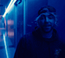 a man in a hat is smiling in a blue light