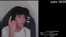 a man wearing headphones is giving the middle finger while sitting in a chair .