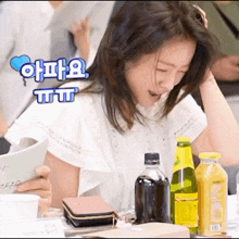 a woman sitting at a table with a bottle of orange juice on the table