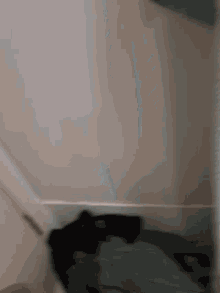 a blurred image of a person standing in a room with a white wall and a door