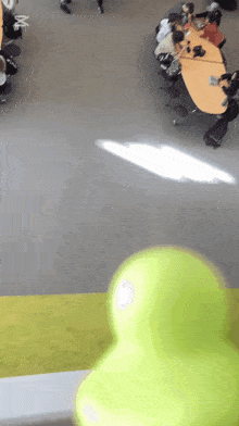 a group of people are sitting at a table in a room with a green ball in the foreground
