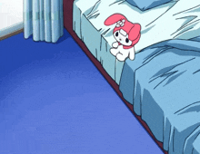 a pink and white stuffed animal is sitting on a bed with blue sheets