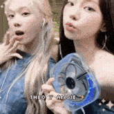 two girls are standing next to each other holding a fan and headphones .