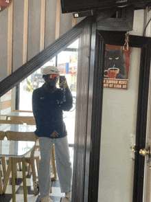 a person taking a picture of themselves in front of a sign that says " calm goodie "