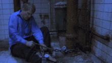 a man in a blue shirt is sitting on the floor with a chain around his feet