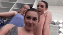 three girls are posing for a selfie in a dressing room