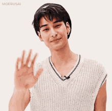 a man in a white sweater is waving his hand .