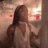 a woman in a white dress is standing in front of a refrigerator door .