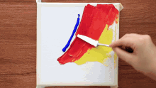 a person is mixing red and yellow paint on a canvas
