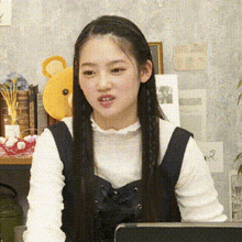 a woman with long hair is sitting in front of a laptop computer and making a funny face .