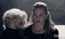 a woman is talking to an older woman in a dark room and making a funny face .