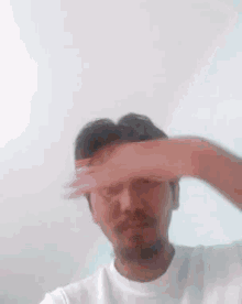 a man is covering his eyes with his hand and looking at the camera .