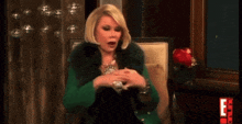a woman in a green coat sits in a chair with a red e on the bottom right