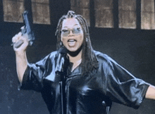 a woman in a leather jacket is holding a gun in front of a microphone ..