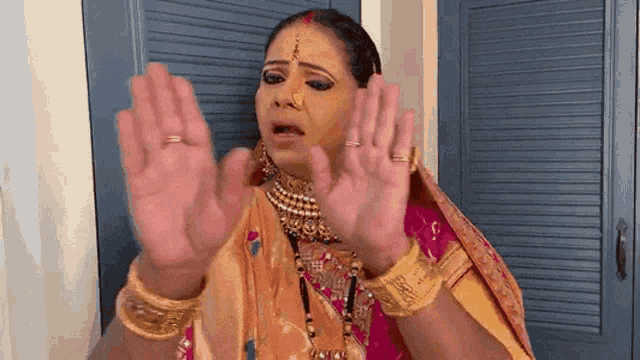 a woman in a sari is making a funny face with her hands in the air . 