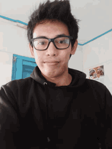 a young man wearing glasses and a black sweatshirt with the letter c on the front
