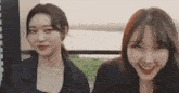 two women are standing next to each other and smiling at the camera .