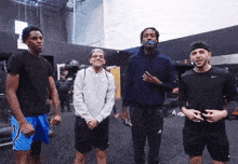 a group of men standing in a gym with one wearing a black nike shirt