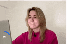 a woman in a pink sweater is looking at a laptop screen that says 0% on it