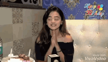 a woman is sitting at a table with a cake and candles .