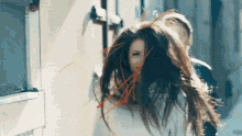 a woman 's hair is blowing in the wind in front of a building