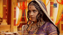 a woman in a purple and gold dress is on a sony television channel
