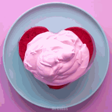 a heart shaped cake with pink whipped cream on a blue plate