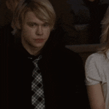 a man in a black shirt and plaid tie is looking at something