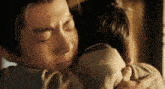 a man is hugging another man with his eyes closed and crying .