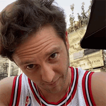 a man wearing a red white and black nba jersey looks at the camera