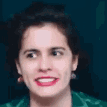 a close up of a woman 's face with a green jacket and earrings .