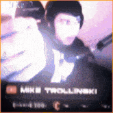 a blurred image of a man with headphones and the name mike trollinski