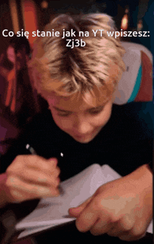 a young boy is writing in a notebook with the words co sie stanie jak na yt wpiszesz zj3b