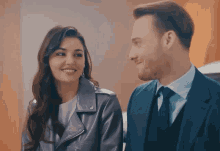 a man in a suit and tie looks at a woman in a leather jacket