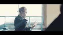 a young man wearing glasses is reading a book