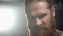 a man with a beard and long hair is standing in front of a light .