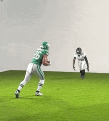 a football player in a green uniform is running with a ball while another player in a white uniform tries to tackle him .