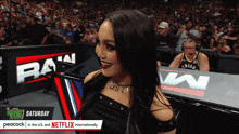 a woman stands in front of a sign that says raw saturday peacock in the us and netflix internationally