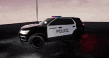 a black and white police car is driving on a road