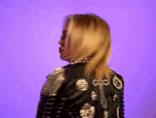 a woman wearing a black jacket with silver buttons on the back