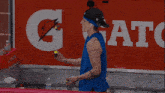 a man in a blue tank top is standing in front of a gatorade sign